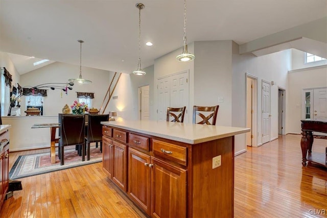 kitchen featuring vaulted ceiling, a center island, decorative light fixtures, and light wood-type flooring