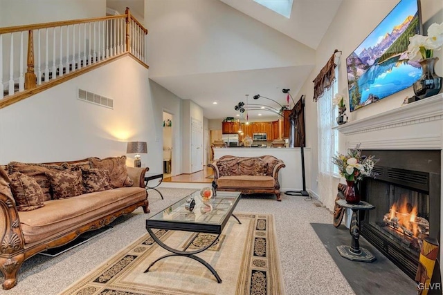 living room with light colored carpet, high vaulted ceiling, and a skylight