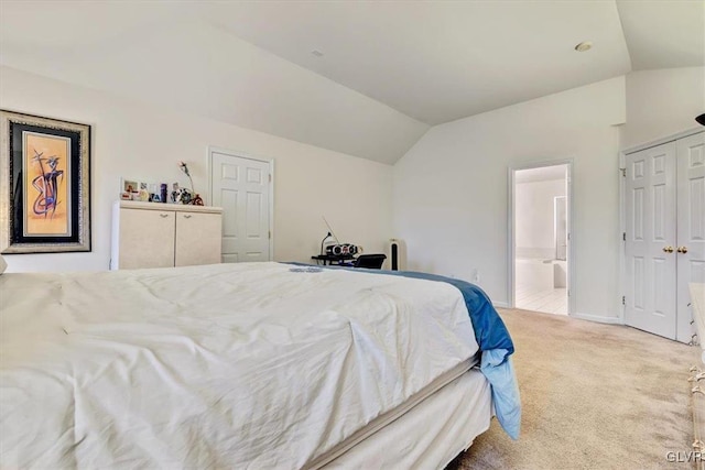 carpeted bedroom with connected bathroom, a closet, and lofted ceiling