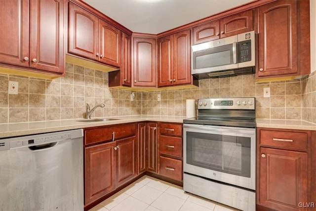 kitchen featuring light tile patterned floors, stainless steel appliances, tasteful backsplash, and sink