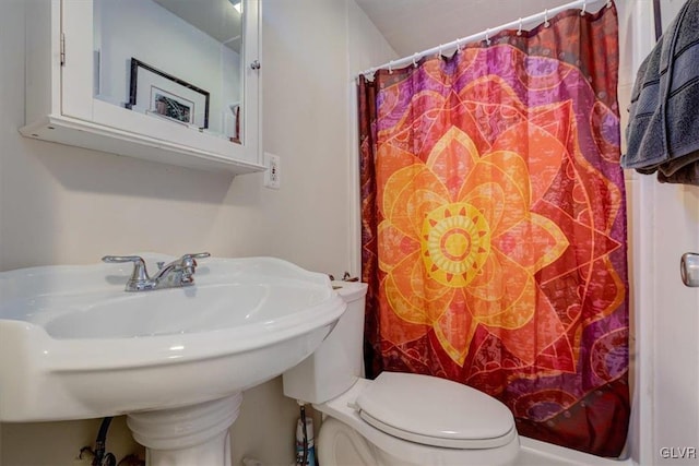 bathroom with a shower with shower curtain, toilet, and sink