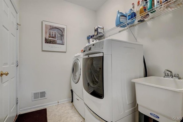 laundry area with separate washer and dryer and sink