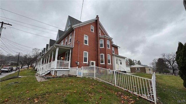 view of side of property featuring covered porch and a yard