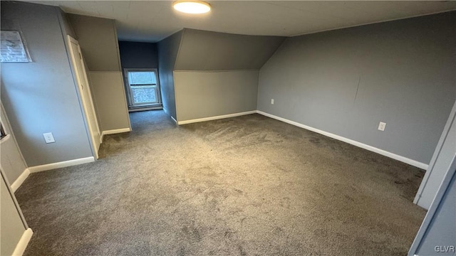 bonus room with dark colored carpet and lofted ceiling