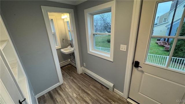 doorway to outside with sink, dark wood-type flooring, and a baseboard heating unit