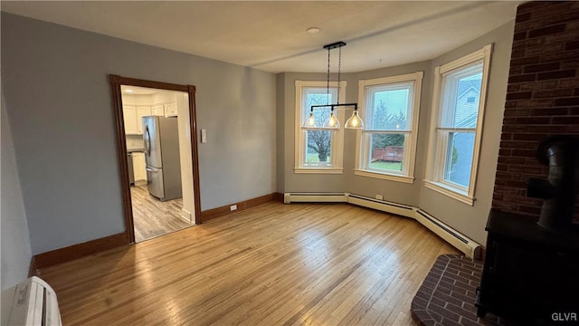 dining space with light wood-type flooring, a wood stove, and a notable chandelier