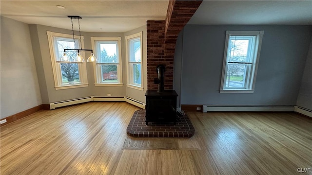 unfurnished living room with hardwood / wood-style flooring, a wood stove, baseboard heating, and a chandelier