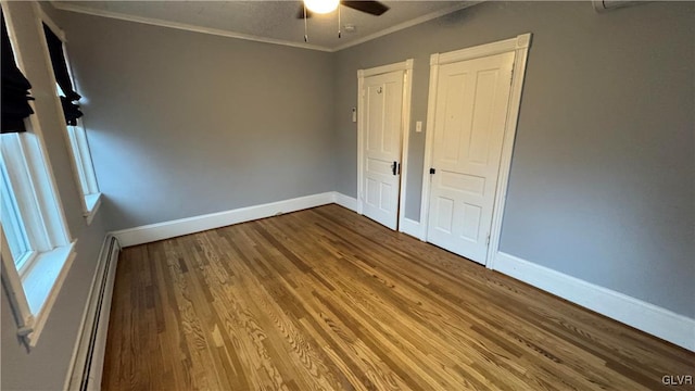 unfurnished bedroom featuring ceiling fan, ornamental molding, hardwood / wood-style flooring, and a baseboard heating unit