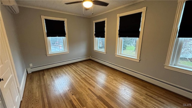 spare room with a baseboard radiator, a wall unit AC, a healthy amount of sunlight, and light hardwood / wood-style floors