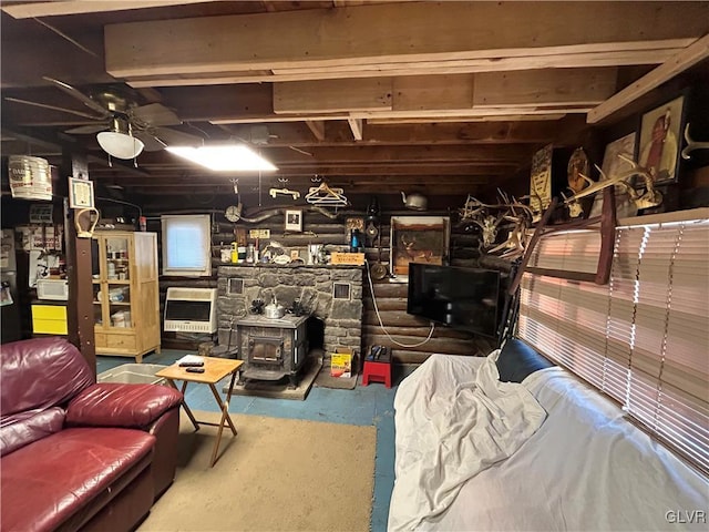 basement featuring a wood stove, ceiling fan, and heating unit