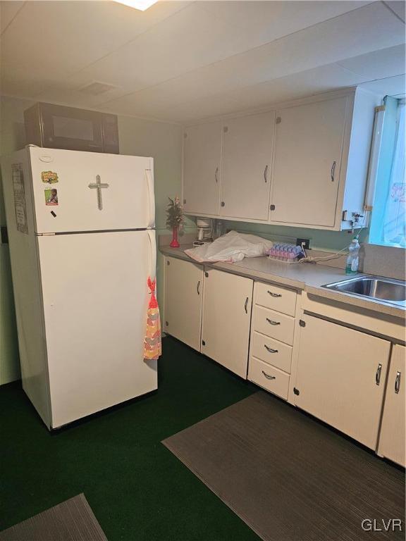 kitchen featuring white cabinets, white refrigerator, and sink