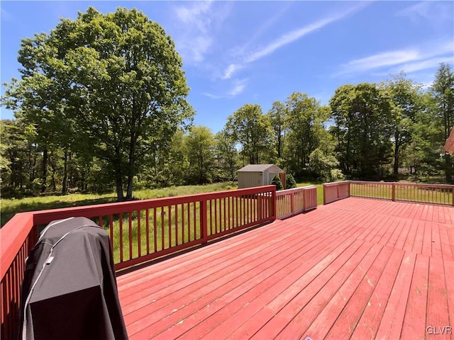 wooden deck featuring an outbuilding and a grill