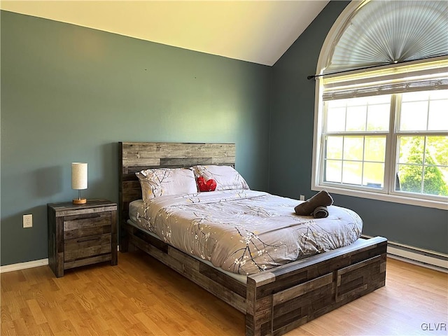 bedroom with baseboard heating, light hardwood / wood-style flooring, and vaulted ceiling