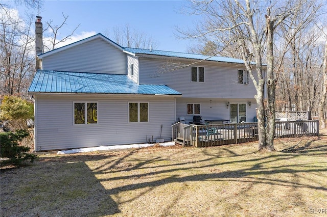 back of property featuring a deck and a lawn