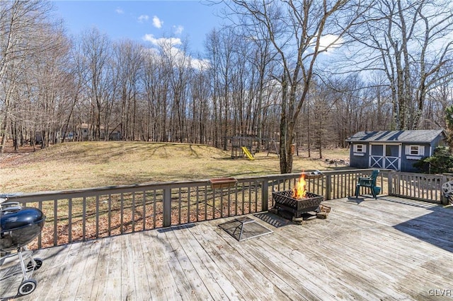 deck with a playground, a grill, an outbuilding, and a fire pit