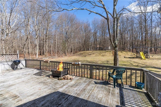 wooden deck with a playground and an outdoor fire pit