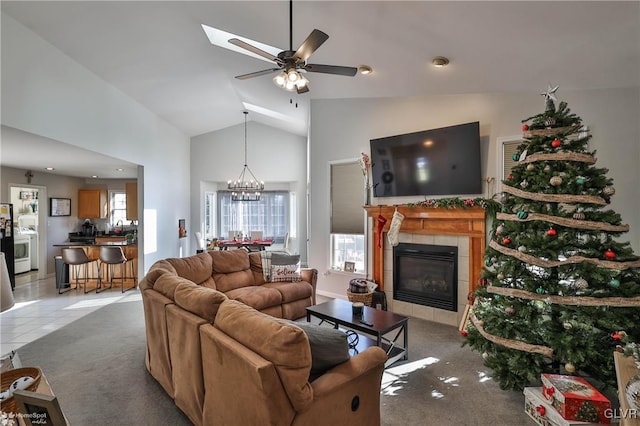 living room featuring ceiling fan with notable chandelier, light colored carpet, lofted ceiling, and a tiled fireplace