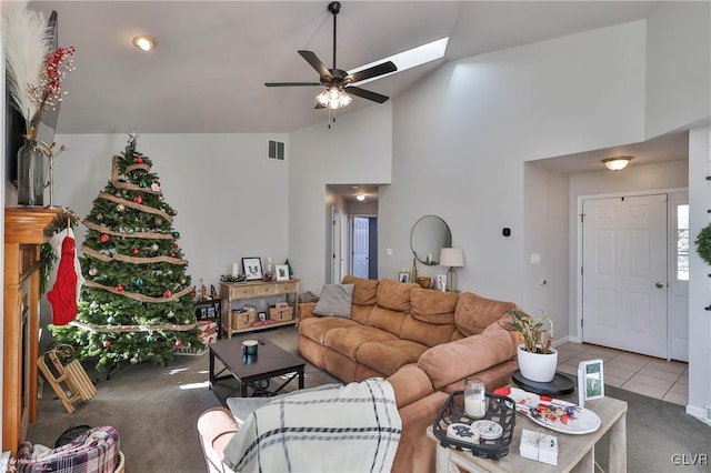 tiled living room with a skylight, ceiling fan, and high vaulted ceiling