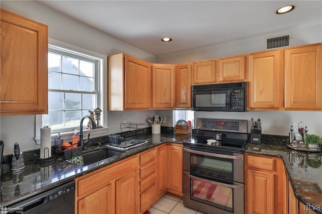 kitchen featuring black appliances, light tile patterned flooring, dark stone countertops, and sink