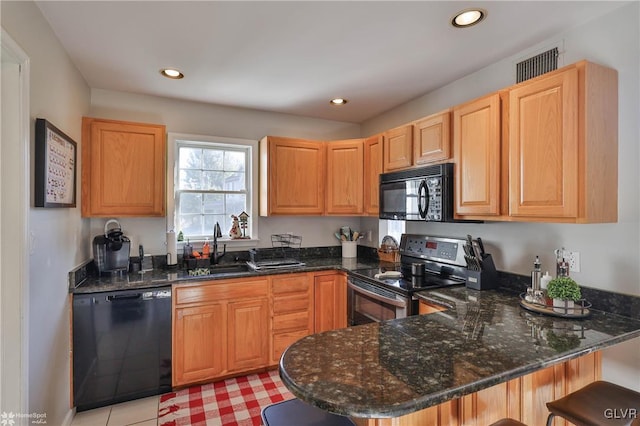 kitchen with kitchen peninsula, sink, black appliances, dark stone countertops, and a breakfast bar area