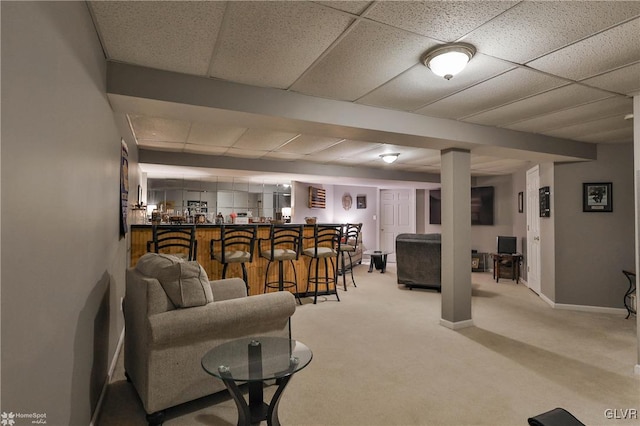 living room featuring a drop ceiling, light carpet, and bar area