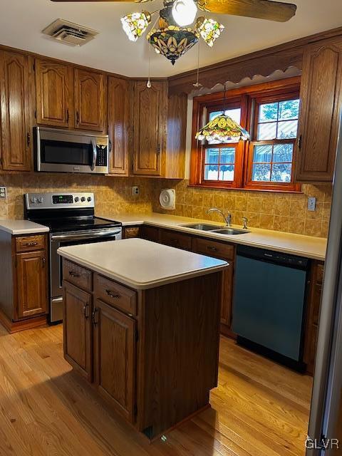 kitchen with light hardwood / wood-style floors, sink, hanging light fixtures, and appliances with stainless steel finishes