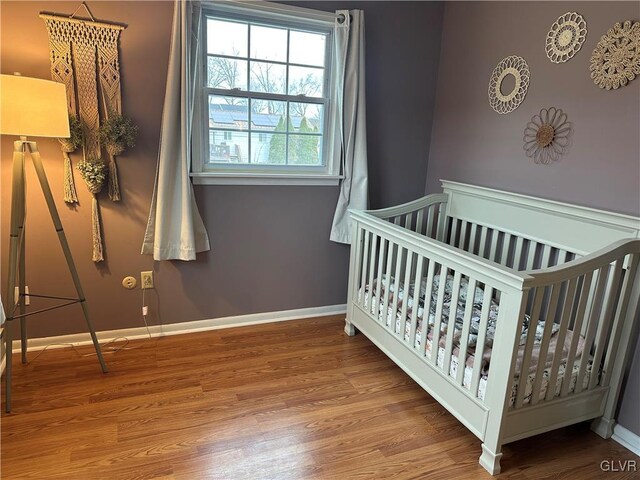 bedroom featuring a crib and wood-type flooring