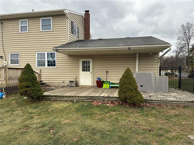 back of property featuring a deck and a lawn