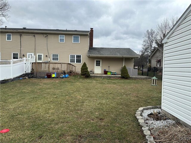 back of property featuring a wooden deck and a yard