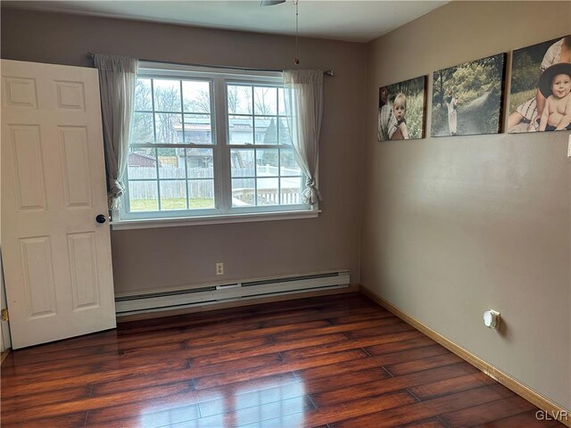 spare room with dark hardwood / wood-style flooring and baseboard heating