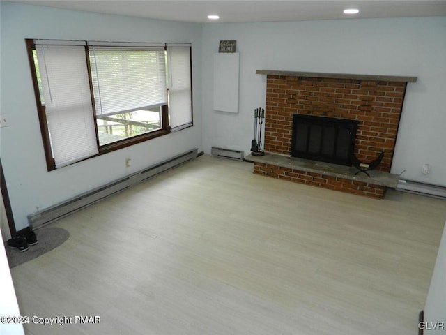 unfurnished living room with a fireplace, light hardwood / wood-style flooring, and a baseboard heating unit