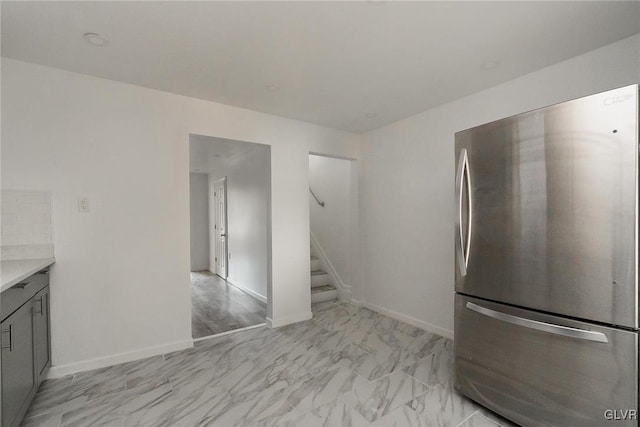 kitchen with stainless steel fridge, gray cabinets, and tasteful backsplash