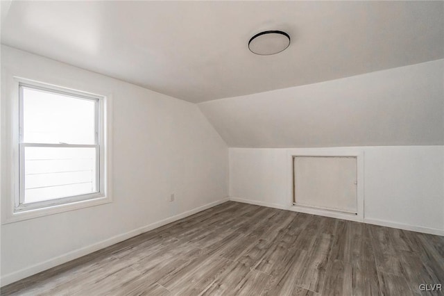 additional living space featuring hardwood / wood-style floors, a healthy amount of sunlight, and vaulted ceiling