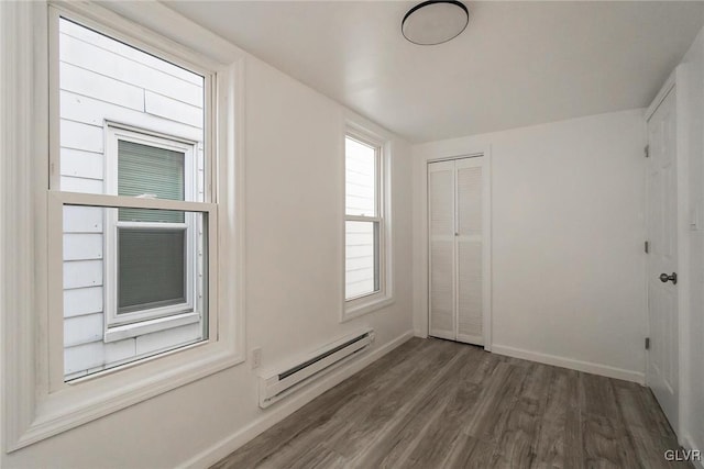 unfurnished room with dark hardwood / wood-style floors and a baseboard heating unit