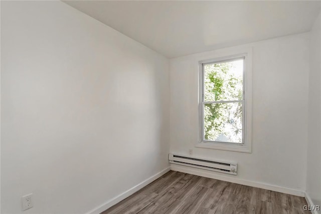 unfurnished room featuring wood-type flooring and a baseboard heating unit