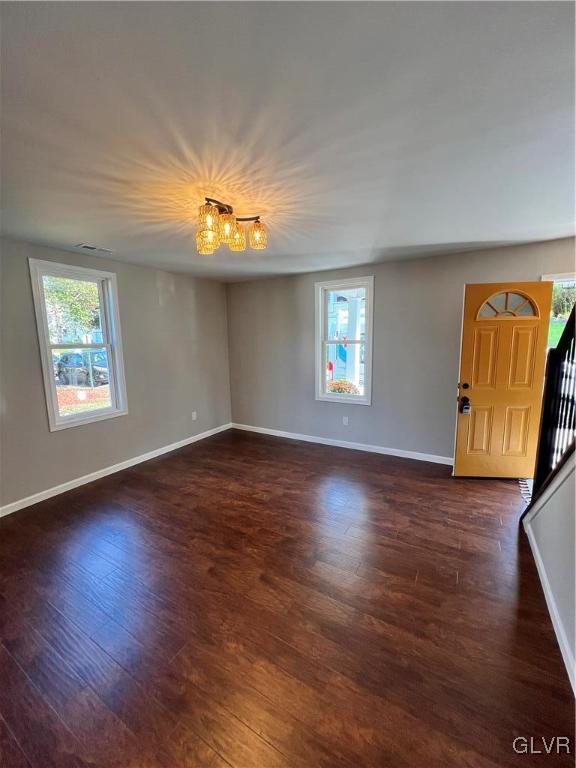 spare room featuring a notable chandelier, dark hardwood / wood-style floors, and plenty of natural light