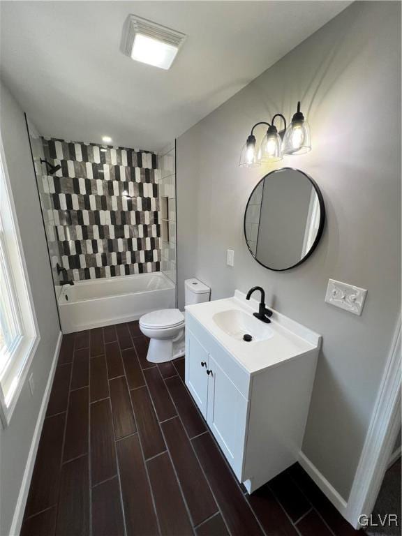 full bathroom featuring vanity, tiled shower / bath combo, and toilet