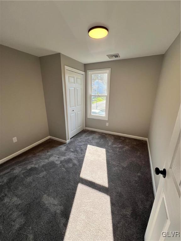 unfurnished bedroom with a closet and dark colored carpet