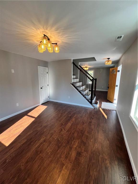 spare room with a wealth of natural light, dark hardwood / wood-style flooring, and a notable chandelier