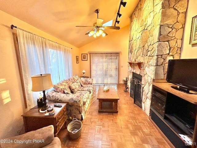 living room with ceiling fan, light parquet floors, track lighting, lofted ceiling, and a fireplace