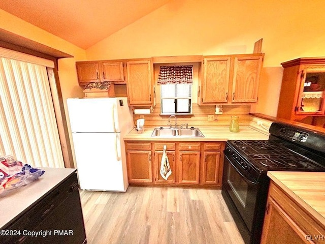 kitchen with sink, light hardwood / wood-style flooring, white fridge, lofted ceiling, and black range