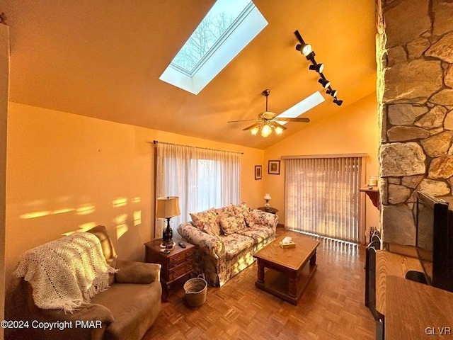 living room with parquet flooring, rail lighting, ceiling fan, and vaulted ceiling with skylight