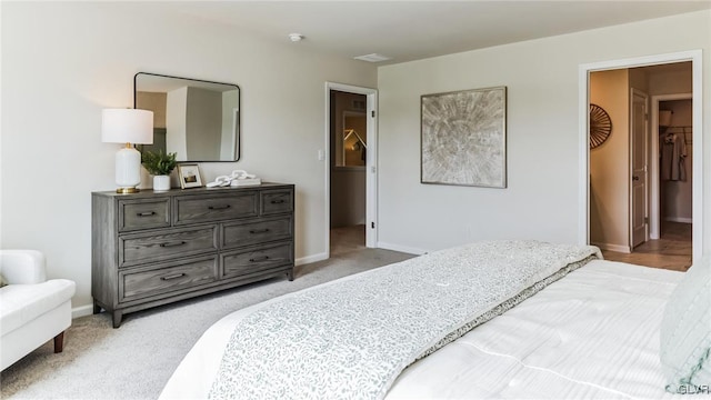 bedroom with a walk in closet and light colored carpet