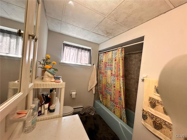 bathroom featuring a drop ceiling, toilet, shower / tub combo, and a baseboard radiator