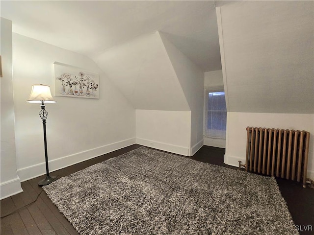 additional living space with dark hardwood / wood-style floors, radiator, and vaulted ceiling