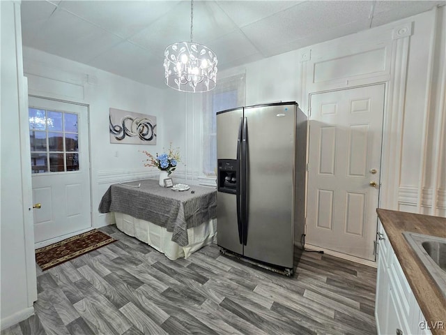 kitchen with an inviting chandelier, wooden counters, hanging light fixtures, hardwood / wood-style flooring, and stainless steel fridge