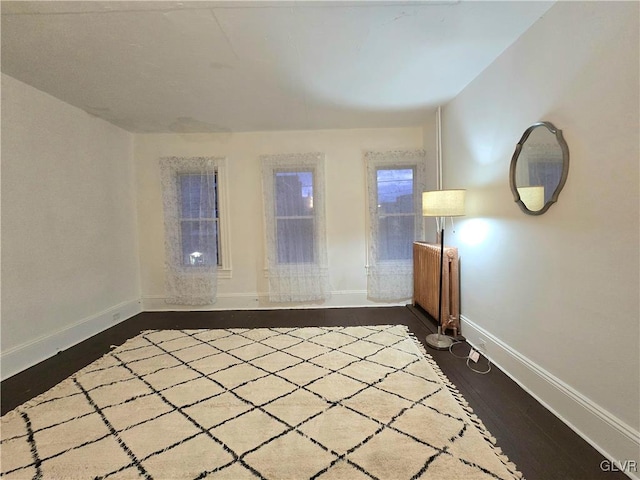 spare room featuring dark hardwood / wood-style floors and radiator heating unit