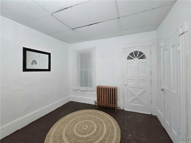 foyer entrance featuring a paneled ceiling, dark hardwood / wood-style flooring, and radiator