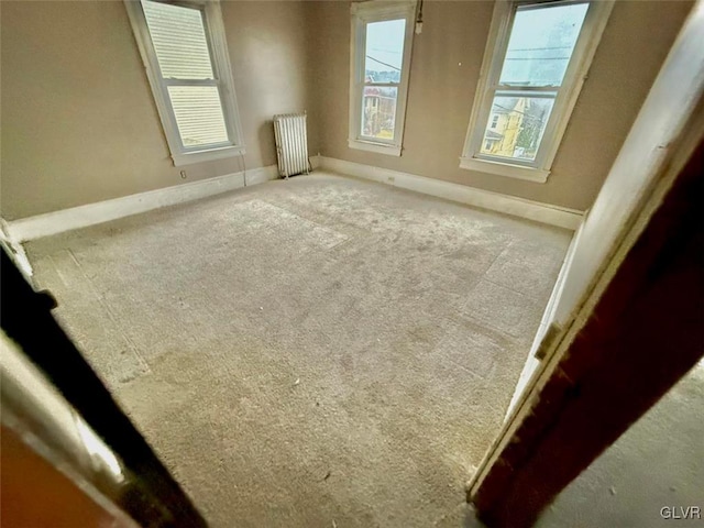 spare room with radiator and carpet