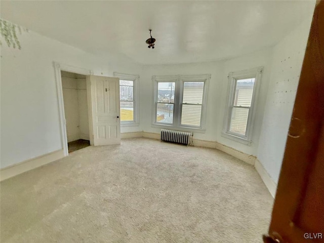 unfurnished bedroom with radiator, light colored carpet, and a closet